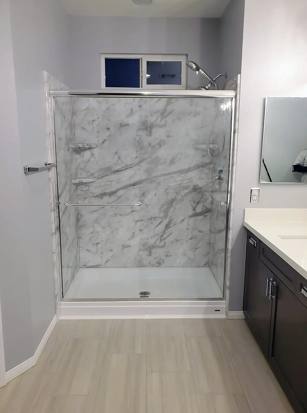 Calacatta Sliding Glass Shower — calacatta-veined shower alcove with polished chrome sliding glass doors, corner shelves and a bright white low-profile base, installed by Revive Bath Solutions in Jacksonville, TX