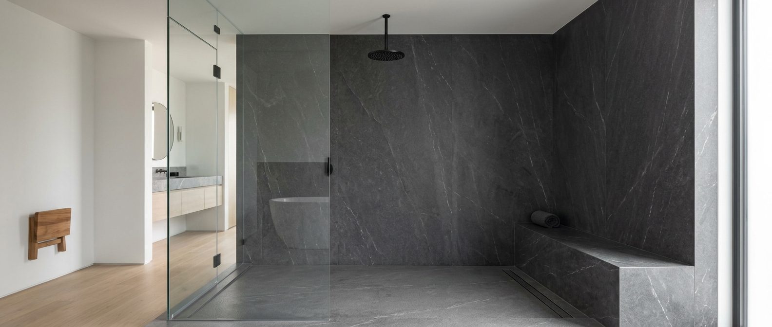 Minimal grout-free walk-in shower with seamless charcoal veined stone panels, frameless glass and a matte black rainfall fixture